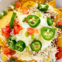 Pernil Nachos · A pile of our fresh chips, creamy queso sauce, slow-roasted pork, beans, tomatoes, green oni...