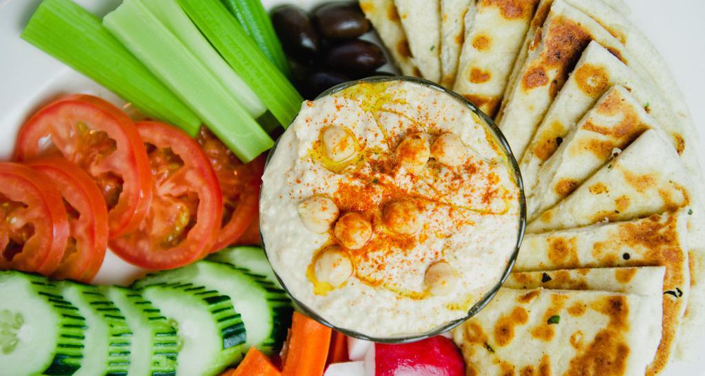 Roasted Garlic Hummus · Vegan. Served with warm griddled pita bread, celery, carrots, cucumber, tomato, radish, and olives.