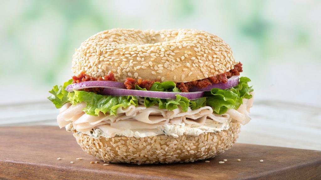 Herby Turkey · Roasted turkey, light herb garlic cream cheese, sun-dried tomato spread, lettuce, and red onions on a sesame bagel.