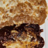 Enchiladas De Mole · Shredded chicken mole enchiladas topped with fresh cheese and served with refried beans and ...