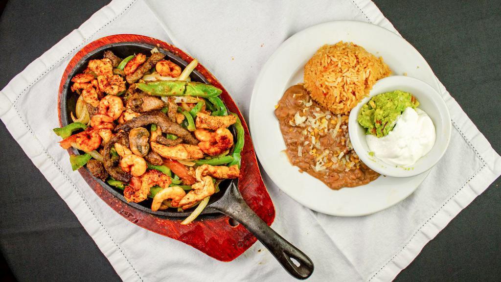 Mixed Fajitas · Steak, chicken, and shrimp, with an exquisite preparation of onion, bell peppers mushrooms, topped with guacamole.