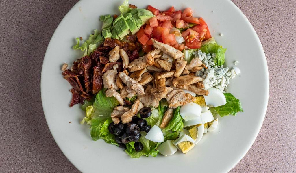 Cobb Salad · Chopped romaine, grilled organic chicken, honey hardwood smoked bacon, tomato, avocado, sliced hard boiled egg, blue cheese crumbles, fried garbanzo beans, blue cheese dressing.