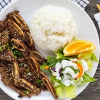 Galbi (Marinated Beef Short Ribs) · Served with steamed rice, green salad, and an orange slice.
