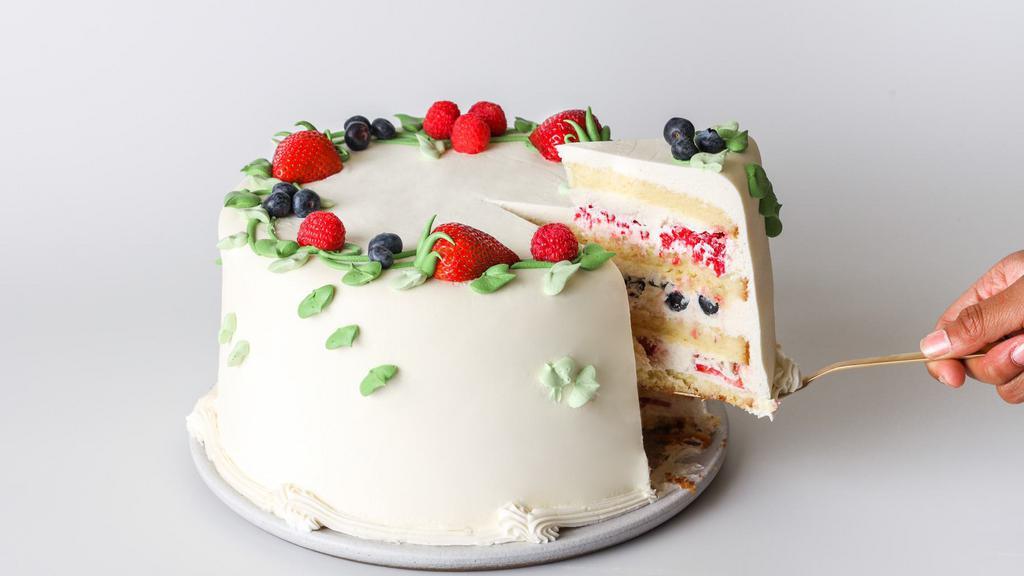 Slice Triple Berry Cake · Yellow butter cake layered with lightly sweetened whipped cream, fresh blueberries, raspberries, and strawberries. Frosted with whipped cream and decorated with buttercream vines