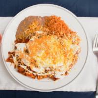 Chilaquiles Con Huevo · The chilaquiles are topped with onion, sour cream, and cheese.