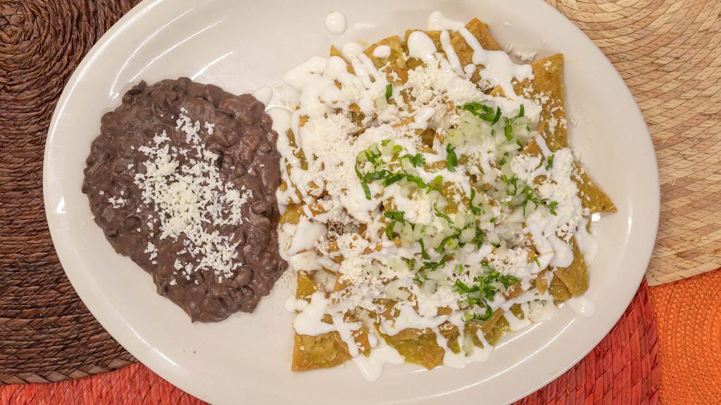 Chilaquiles Verdes · The classic Mexican breakfast cure-all. Crisp tortilla chips, sautéed in our home-made Green Tomatillo Sauce, and served with Refried Black Beans. Garnished with Queso Fresco, Crema Mexicana, Onion, and Cilantro.