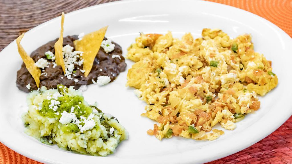 Huevos A La Mexicana · Eggs, scrambled with fresh Tomato, Onion, and Chile Serrano. Served with Salsa Verde cruda, Queso Fresco, Onion, and Cilantro.