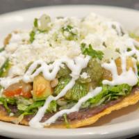 Tostada - Calabacitas · Toasted corn tortilla, refried black beans, shredded lettuce, Mexican squash, and roasted co...