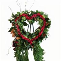 Forever In Our Hearts · Heart shaped standing wreath, framed in season greenery surrounding dozens of red roses. Fin...