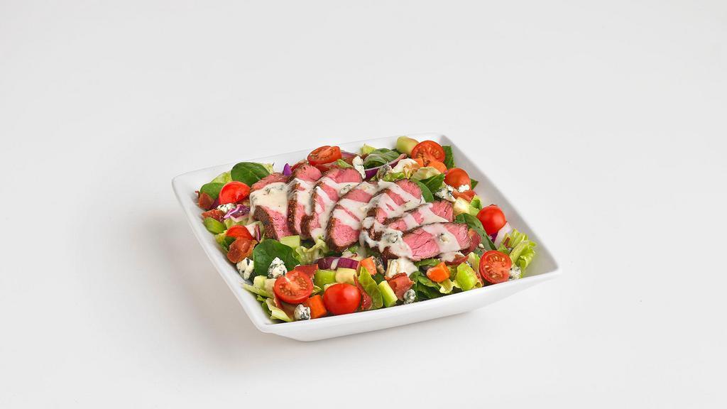 Steak Chopped Salad · Tender, grilled steak piled on top of fresh mixed greens tossed, in a balsamic dressing with cherry tomatoes, cucumber, celery, carrot, and red onion. Garnished with bleu cheese and bacon crumbles, then drizzled with a bleu cheese cream sauce.