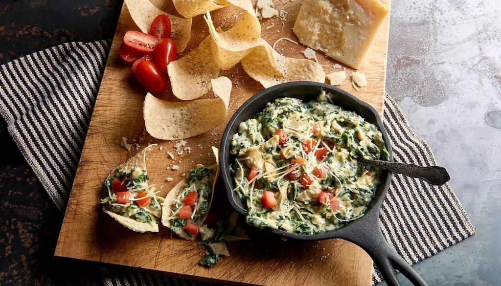 Spinach Artichoke Dip · Slow-baked with four cheeses and served with crisp tortilla chips.
