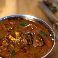 Goat Curry · Goat curry with bones mixed with herbs and spices with tomatoes and onions.
