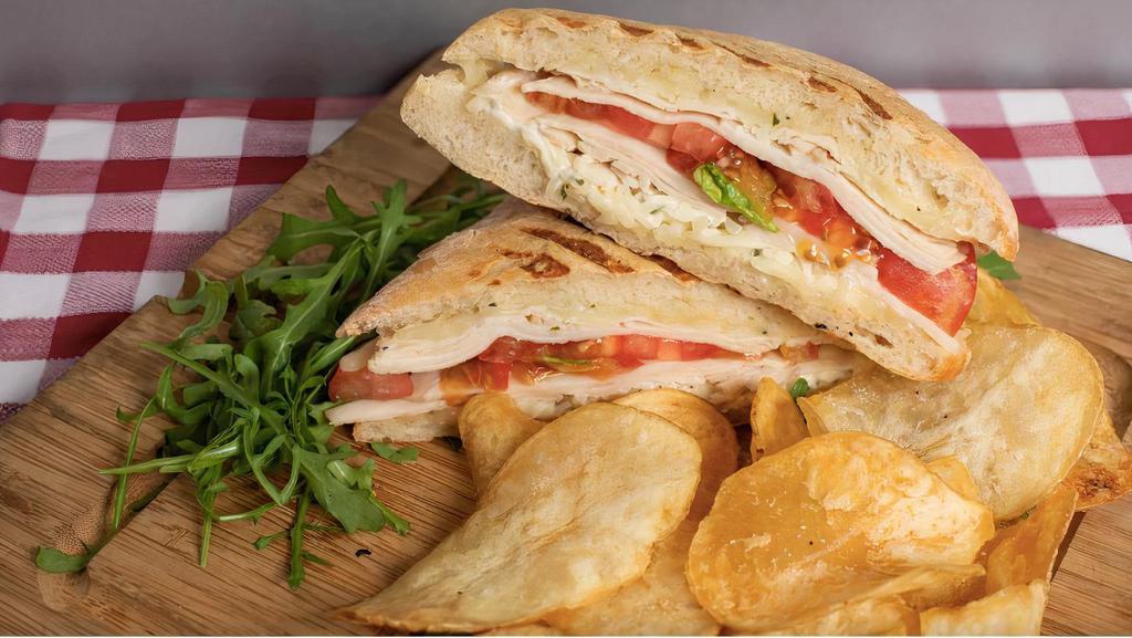 Turkey Swiss Panini · Sliced whole breast turkey, swiss cheese, basil pesto, and mayonnaise on freshly grilled ciabatta bread with housemade potato chips and a side of spicy brown mustard.