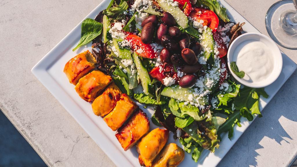 Organic Chicken Salad · Mixed greens, roma tomato, cucumber, kalamata olives, topped with feta cheese. Made with organic chicken breast skewer. Served with a balsamic vinaigrette dressing and garlic sauce. Served with balsamic vinaigrette dressing and garlic sauce.