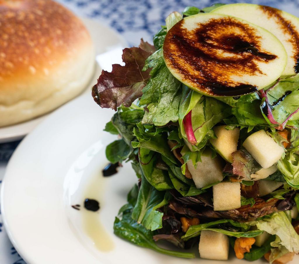 Vegan Manchego Salad · Compressed organic mixed greens, granny smith apples, caramelized walnuts, dates  in our pear dressing with olive oil & a balsamic reduction  (served without Manchego) • dressing on the side not available •