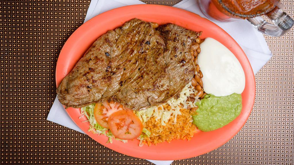 Carne Asada · Two grilled thin sirloin steaks. rice beans sour cream guacamole lettuce and tomato.