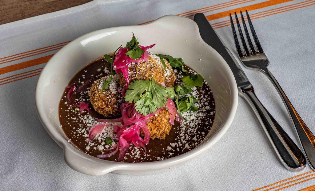 Croquettes · Croquettes filled with adobo braised chicken, served over black bean puree topped withe pickled red onion and a side of cantina hot sauce
