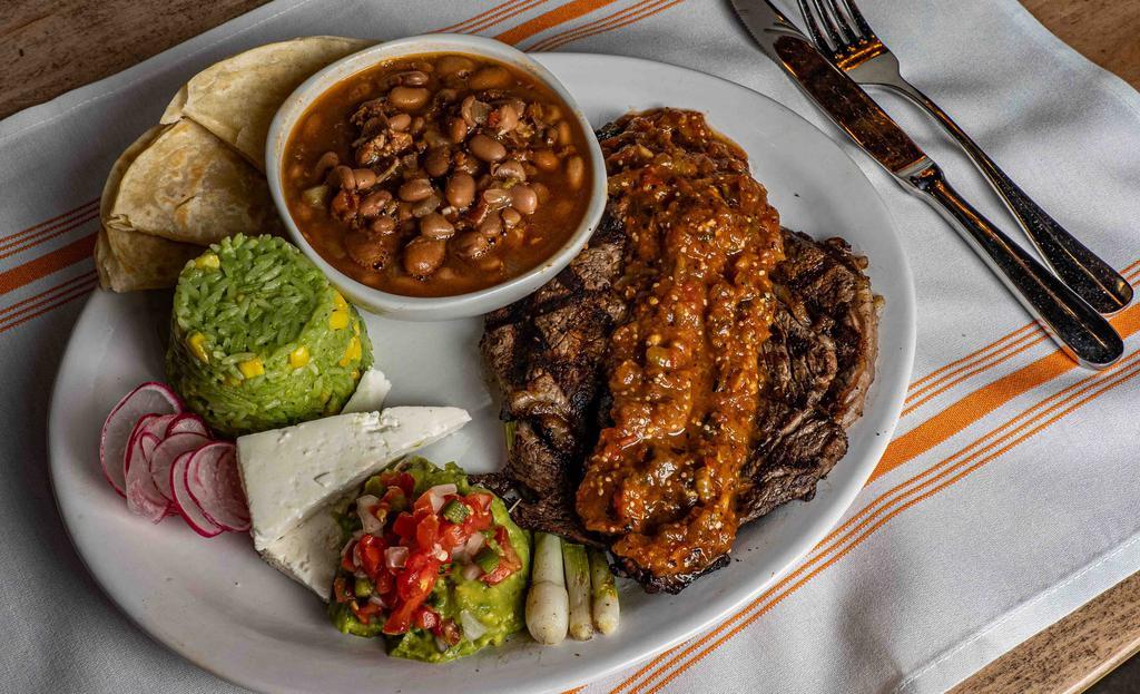 Ranchero Steak · Our salute to Tex-Mex - 12oz grilled ribeye, ranchero sauce, house made flour tortillas, queso fresco, guacamole, grilled spring onions, Polanco rice & charro beans