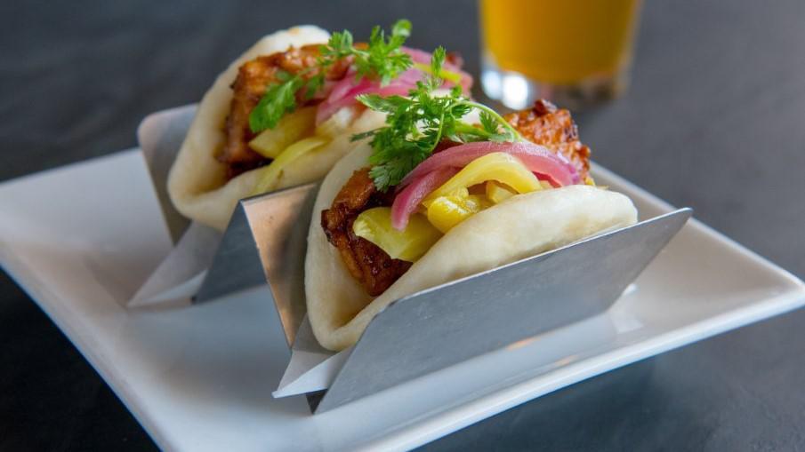 2 Pieces Pork Belly Bao · Braised pork belly, pickled mustard greens, pickled red onion, hoisin, Sriracha and cilantro in fluffy steamed buns.