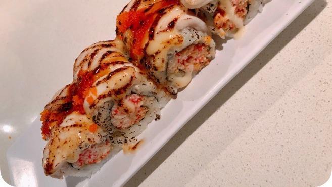 Domo Agitato Roll · Spicy tuna and crab mix topped with torched white fish, teriyaki sauce, white sauce, masago.
