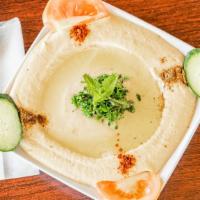 Hummus · A creamy dip of garbanzo beans, tahini, garlic, lemon and drizzled with olive oil, served wi...