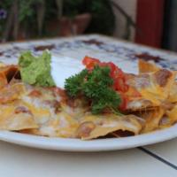 Nachos Supreme · Fresh corn chips topped with your choice of beef or chicken, refried beans, melted cheese, f...