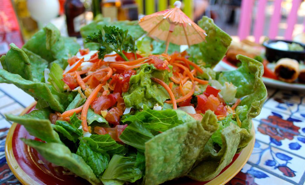 Tostada Vegetariana · A deep-fried, bowl-shaped spinach flour tortilla filled with refried beans, Mexican rice, crisp lettuce, and chopped tomatoes, topped with fresh carrots and cucumbers. Vegetarian-friendly.
