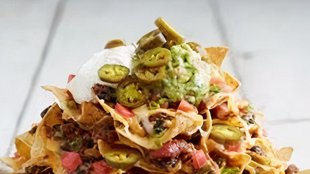 Nachos Volcano · Corn tortilla chips with melted jack and cheddar cheese, refried beans, pico de gallo, sour cream, guacamole and jalapenos.