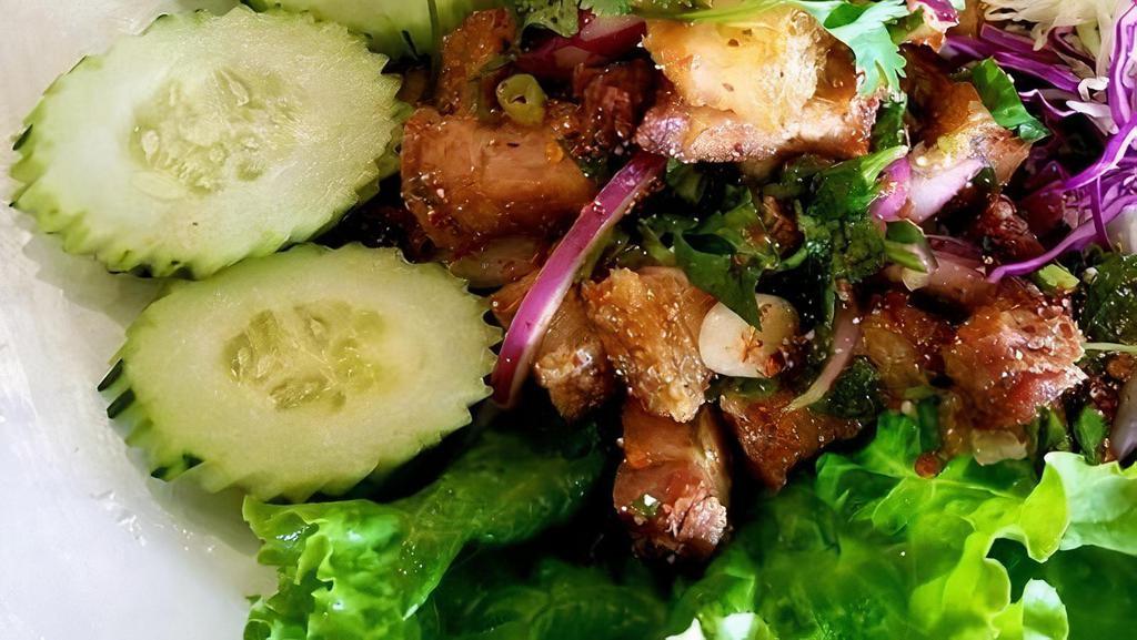 Larb Moo Kob · Crispy pork belly sautéed and tossed in lime dressing with toasted rice powder, chili powder, cilantro, mint leaves, and onion.
