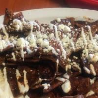 Mole Chilaquiles · Homemade chips smothered in mole topped with sour cream, queso fresco, served with two eggs ...