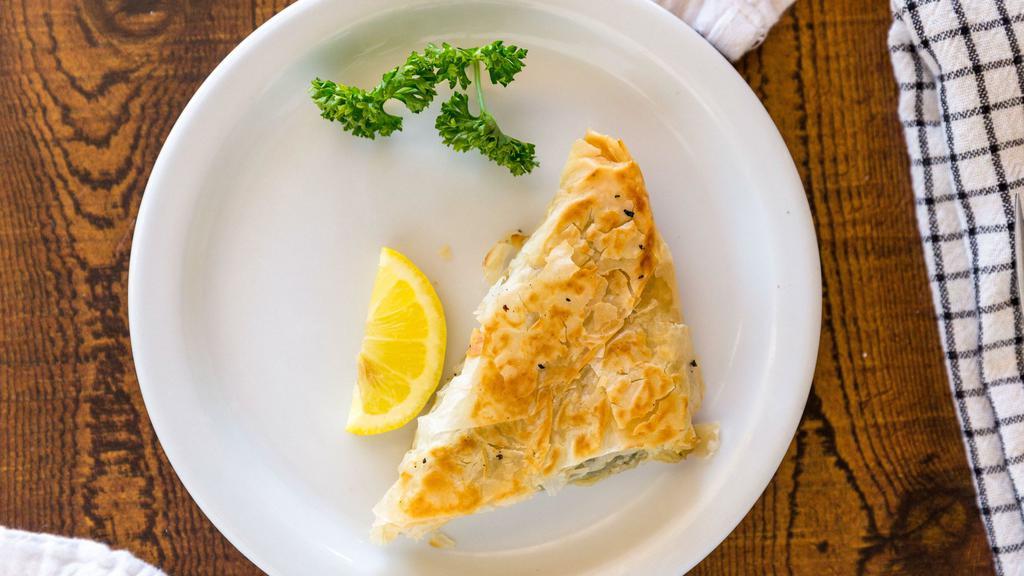 Spanakopita · A triangular shaped phyllo pastry filled with spinach and feta cheese.
