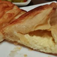 Tyropita · A triangular shaped phyllo pastry filled with feta and cream cheese.