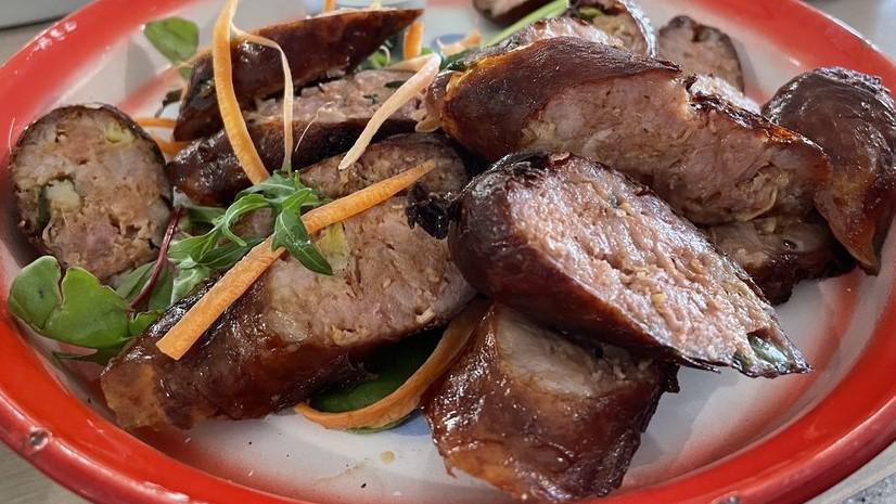 Lao Sausages (Sai Oua Moo) · Northern Lao style sausages, ground pork, lemongrass, herbs, served with purple or white sticky rice.
