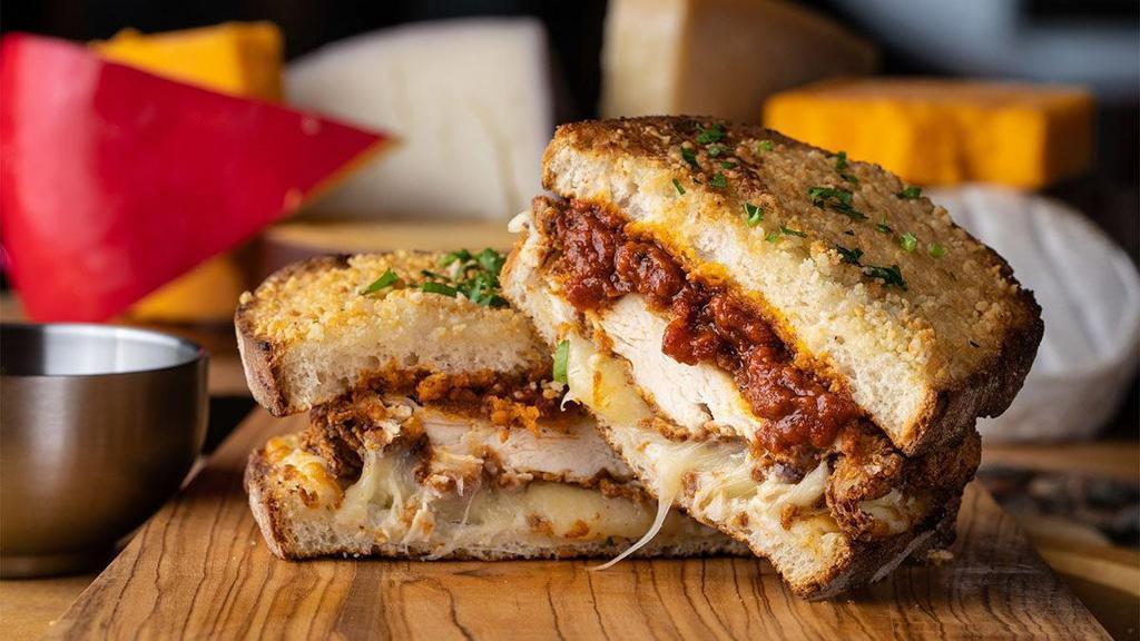 The God'Feather · toasted parmesan crusted sourdough, creamy herb cheese, triple stacked with cheddar, mozzarella & provolone cheeses with fried chicken breast, spicy tomato sauce & parmesan cheese, PLUS extra spicy tomato sauce for dipping