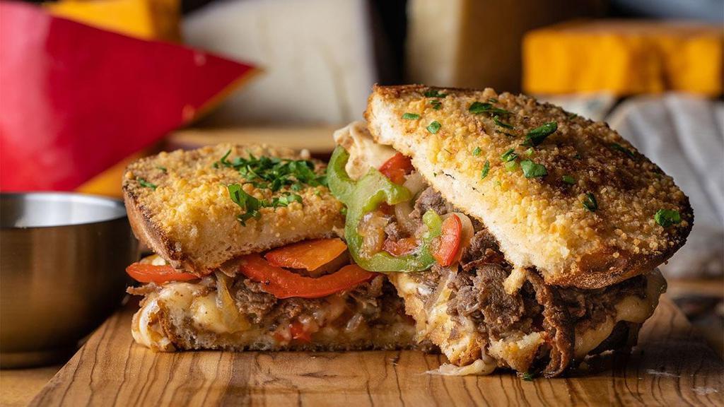 The Sir Lion · toasted parmesan crusted sourdough, creamy herb cheese, triple stacked with cheddar, mozzarella & provolone cheeses with shaved sirloin steak, caramelized peppers & onions, side of “cheese whiz” for dipping