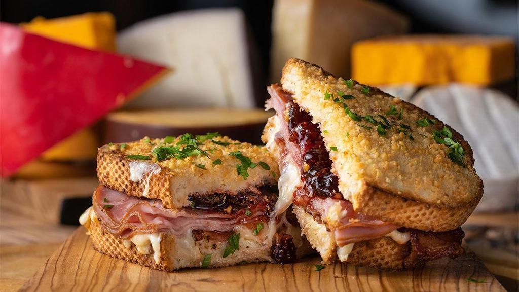 Bacon Hamma Jamma · toasted parmesan crusted sourdough, creamy herb cheese, triple stacked with cheddar, mozzarella & provolone cheeses with sliced smoked ham, crispy bacon & bourbon “old fashioned” jam