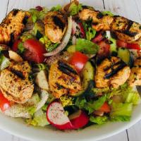 Leon Chicken Salad · Fattoush salad topped with two skewers of chicken.