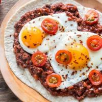 Huevos Rancheros · 2 over easy eggs on tortilla topped with salsa roja, served with side of black beans, tortil...