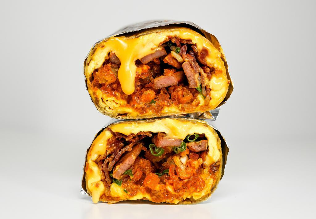 The One · 3 slices of crispy thick-cut bacon, sauteed chicken apple sausage, triple egg omelet, chili aioli, gooey American cheese, scallions and fried potato tots seasoned with Nashville spices all encased in a toasted flour tortilla and made with love.