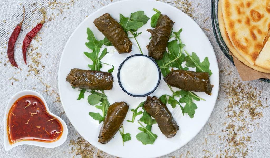 Stuffed Grape Leaves (Dolmas) · Grape leaves stuffed with rice and flavorful herbs. Served with yogurt.  Comes with a pita bread. (6 Pieces)