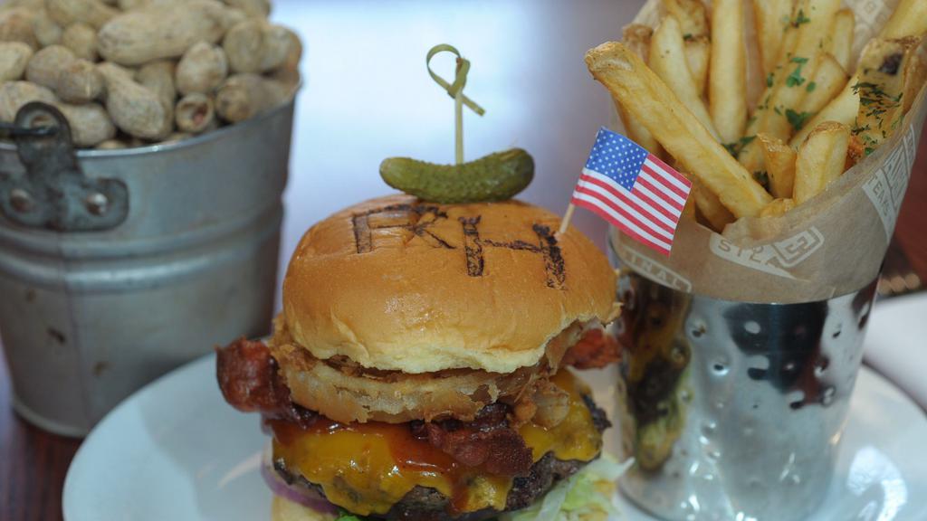 All-American Burger · Topped with onion rings, two slices of crisp bacon, BBQ sauce and mild cheddar cheese.