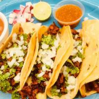 Tacos Al Pastor · Four tacos filled with pork meat with special sauce, pineapple, cilantro and onions served w...