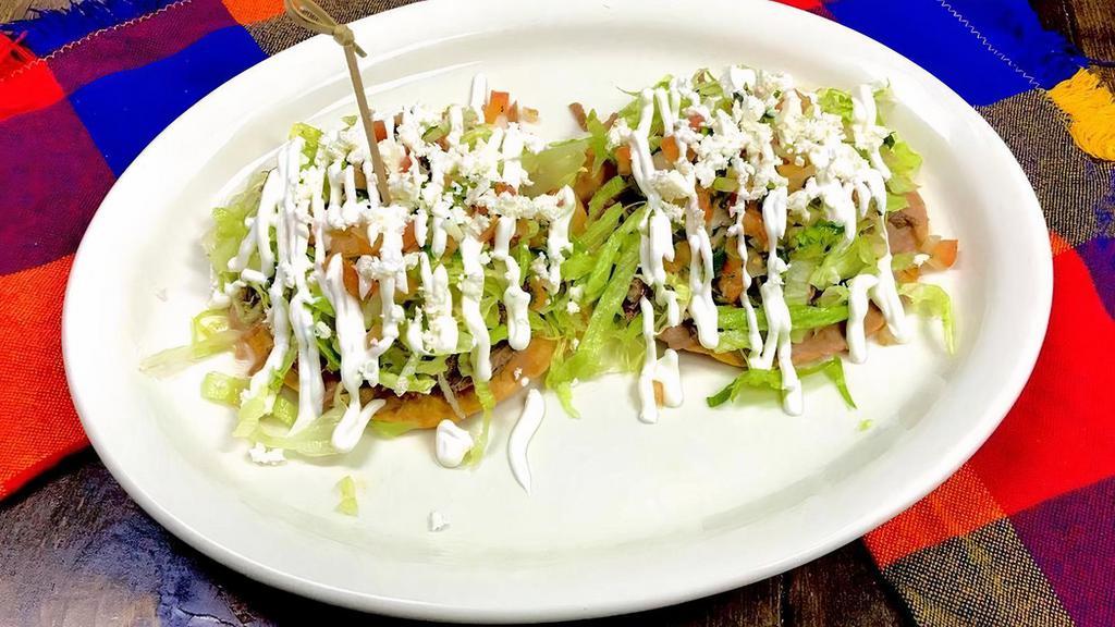 2 Tostadas Village · Crunchy tostadas include your favorite choice of meat, a thin layer of refried beans, lettuce, pico de gallo, sour cream, and fresh cheese on top.