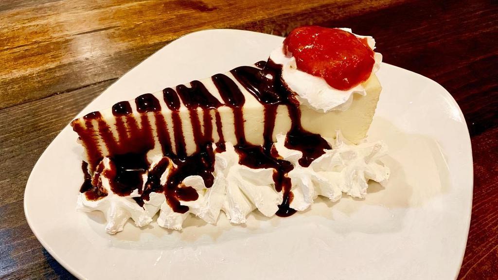 Cheesecake · Creamy classic cheesecake slice with whipping cream on the sides, a hint of strawberry sauce and chocolate syrup drizzle.