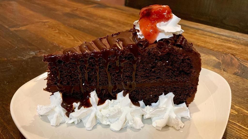 Chocolate Cake · Chocolate rich slice of cake with whipping cream on the sides, a hint of strawberry sauce and chocolate syrup drizzle.