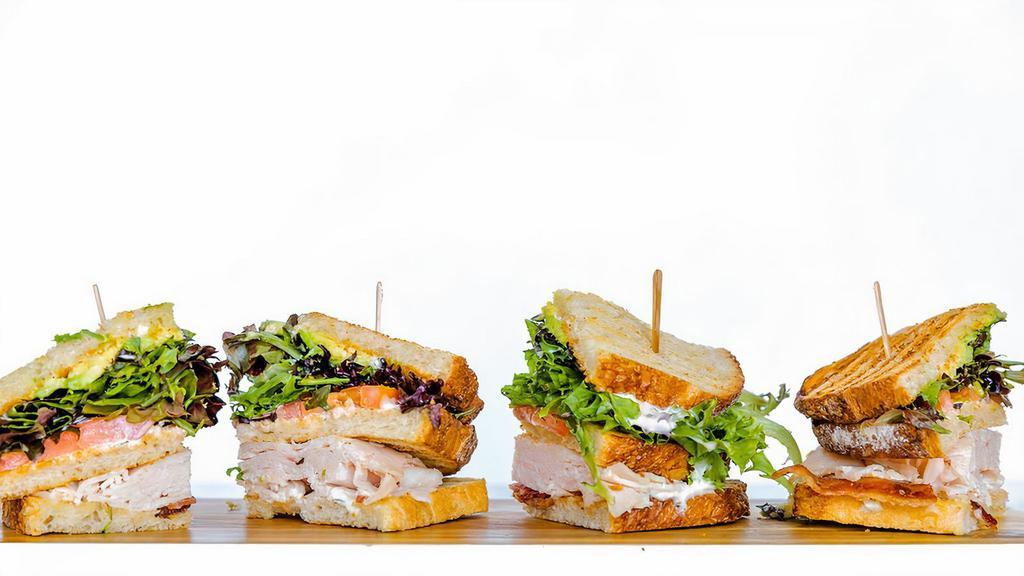 Turkey Club · Turkey, Applewood Smoked Bacon, Mixed Greens, Tomato, Avocado, Herb Aioli on Toasted Sourdough|Served with Ranch Chips.