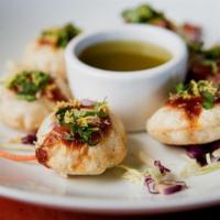 Pani Puri · crispy-fried puffed ball that is filled with potato, chickpeas, onions, spices, and flavored...