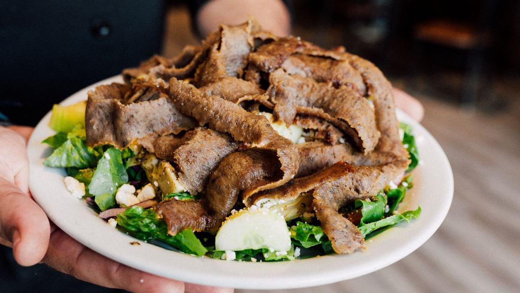 Gyro Salad · Chopped spring greens with your choice of any of our three gyro meats, beef and lamb, pork, or chicken, tomatoes, cucumber, Kalamata olives, marinated artichoke hearts, Feta cheese, and topped off with our house dressing.