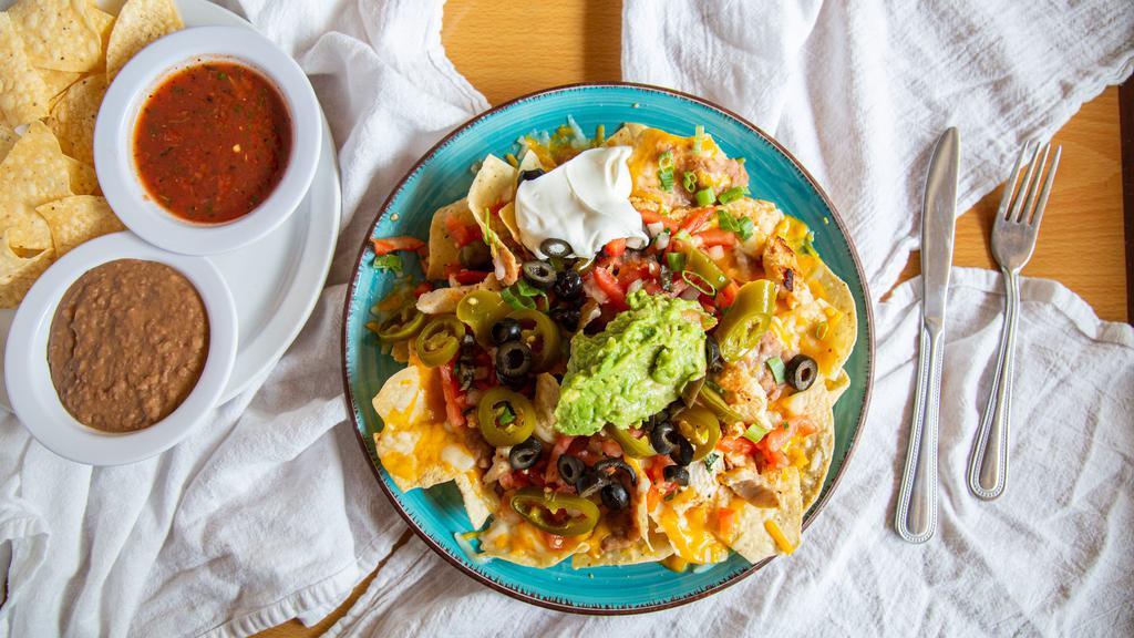 Los Pinos Nachos · Crispy tortilla chips topped with cheese, refried beans, tomato, green onion, olives, jalapeños, guacamole and sour cream.