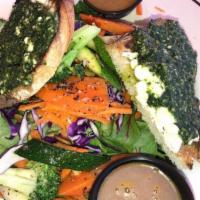 Goat Cheese Salad · Mixed baby greens, warm marinated goat cheese log, and sautéed vegetables with basil pesto a...